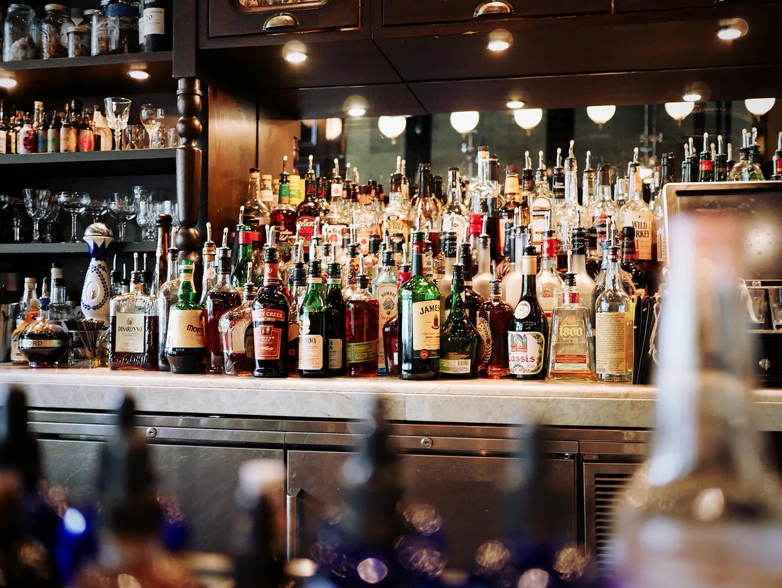 Oga's Cantina: A well-stocked bar counter features rows of liquor bottles and glassware under warm lighting.