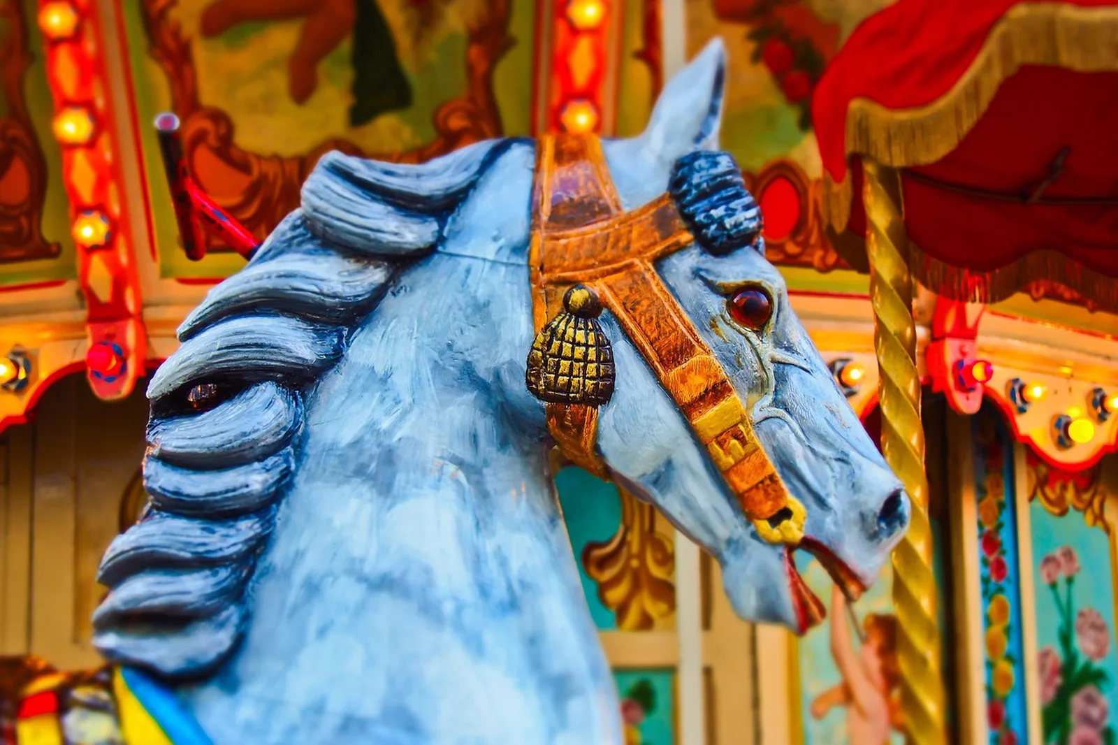 Fun Fair: Close-up of a brightly painted blue carousel horse with decorative lights in the background.