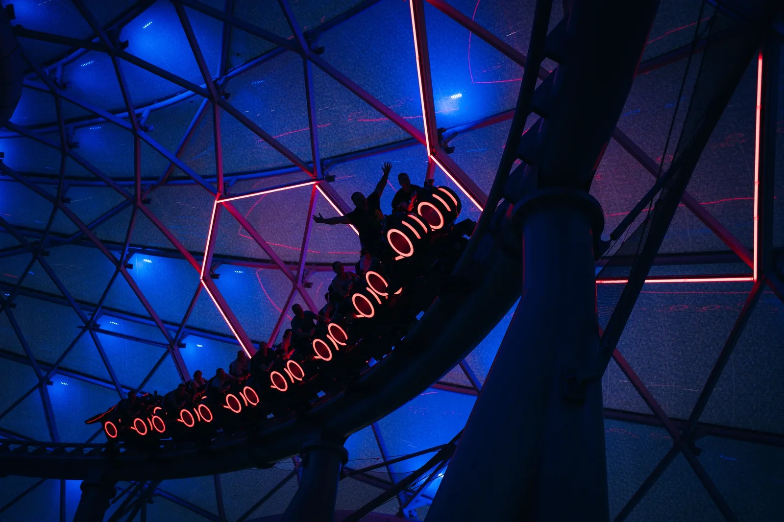 Harry Potter and the Forbidden Journey: A futuristic indoor roller coaster train decorated with red neon lights speeds along a track under a dome structure.