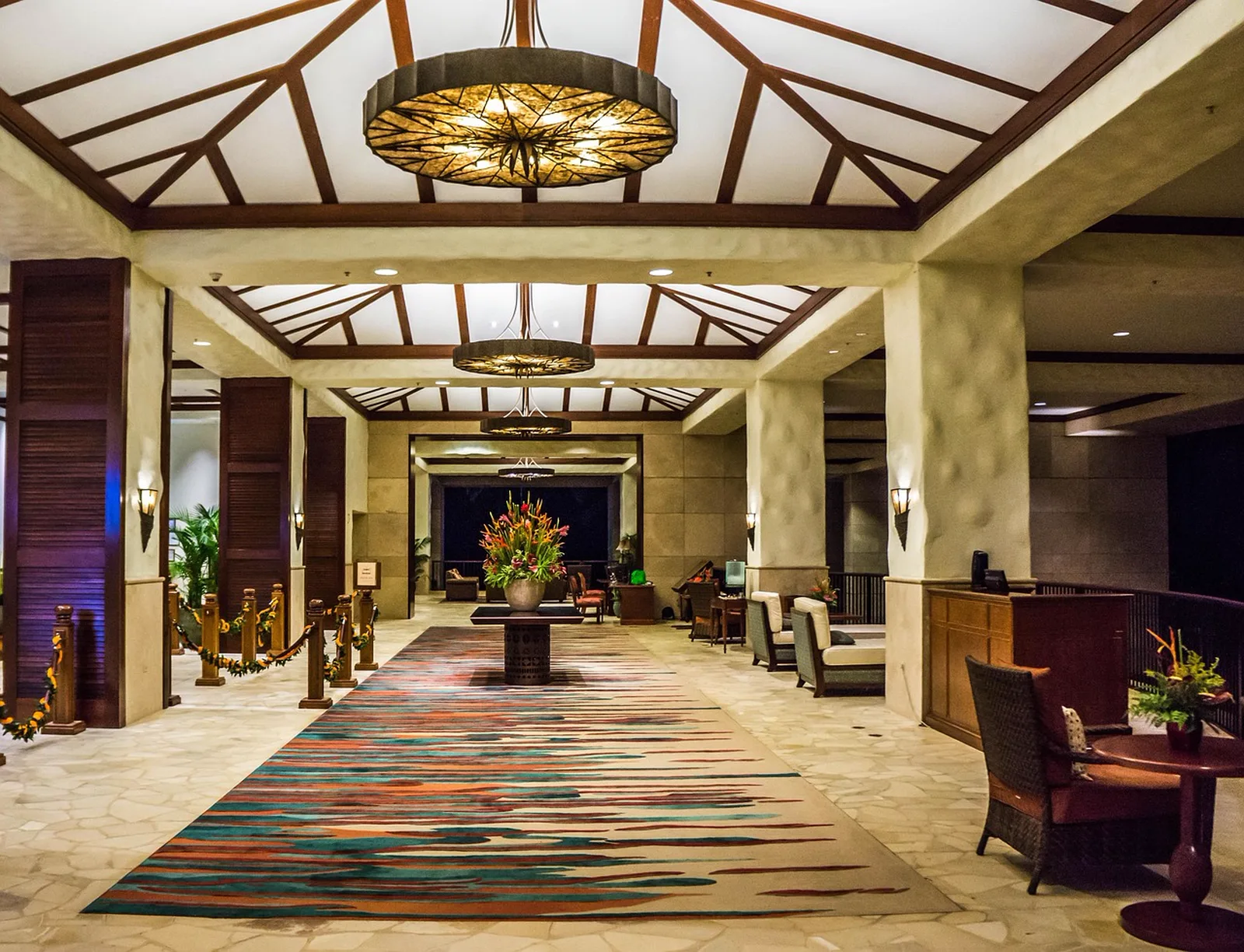 Disney's Contemporary Resort: A spacious luxury resort hotel lobby featuring high wooden ceilings, large chandeliers, and a colorful runner rug.