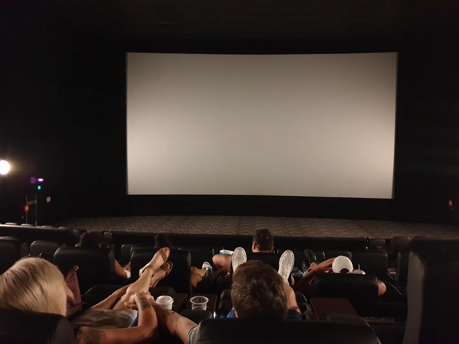 LEGO Galaxy: Audience members sit in reclined seats in front of a large blank screen inside a dark movie theater.