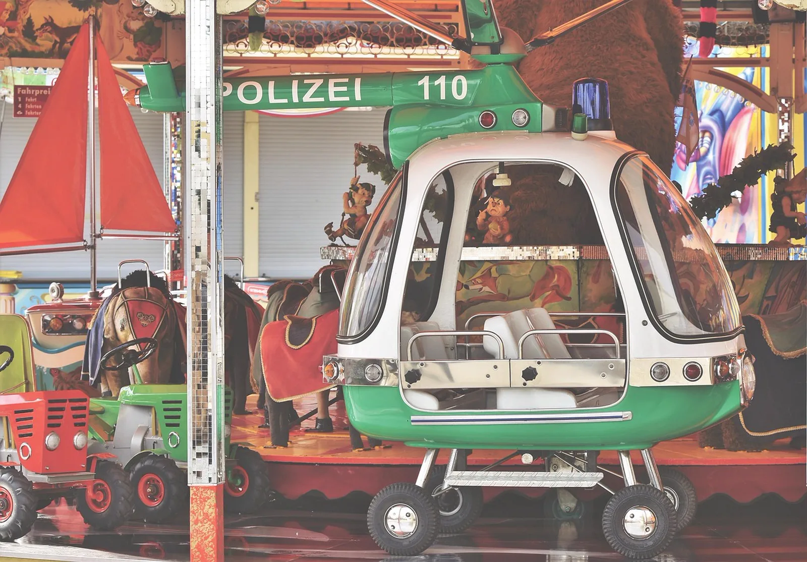 Royal Joust: A children's fairground carousel featuring a toy police helicopter vehicle and small tractor.