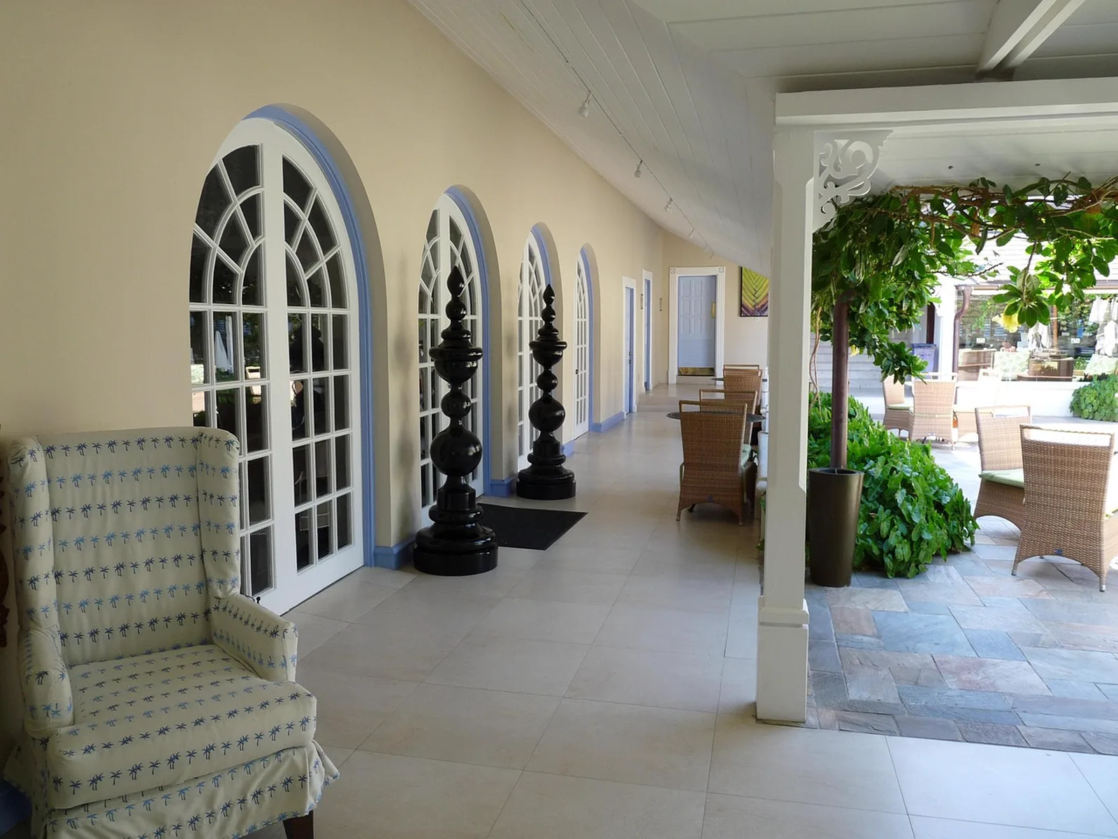Disney's Caribbean Beach Resort: A covered patio with arched French doors, decorative black finials, and wicker seating leading to an outdoor courtyard.