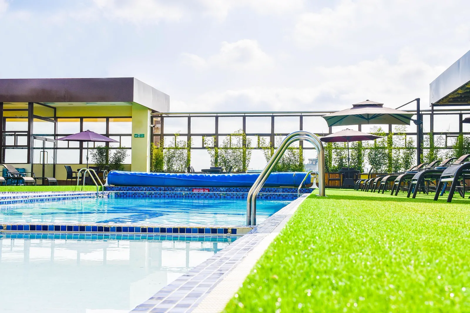 Disney's Port Orleans Resort - Riverside: An outdoor swimming pool surrounded by artificial turf, lounge chairs, and patio umbrellas.