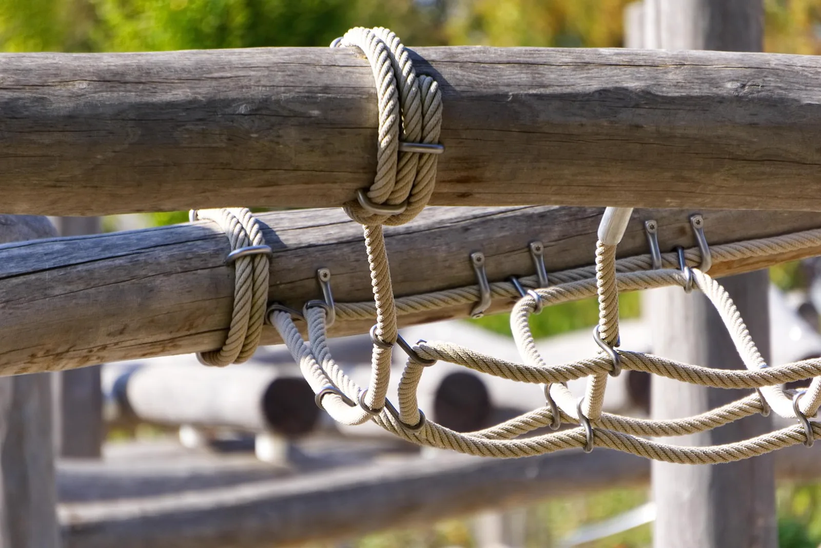 DreamWorks Land: A close-up view of wooden logs and climbing ropes on an outdoor playground structure.