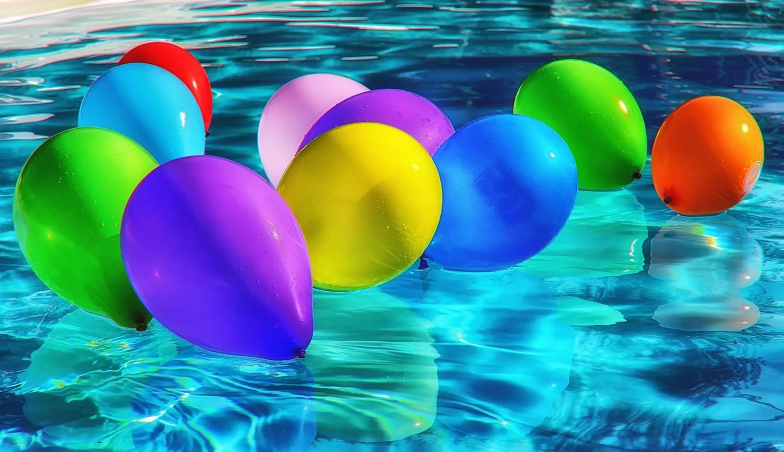 SEA LIFE Aquarium: Colorful inflated balloons float on bright blue swimming pool water in sunlight.
