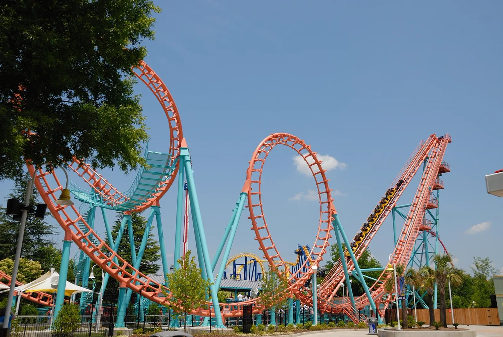 Goofy's Sky School: A colorful steel roller coaster features loops and inversions against a clear blue sky at a theme park.