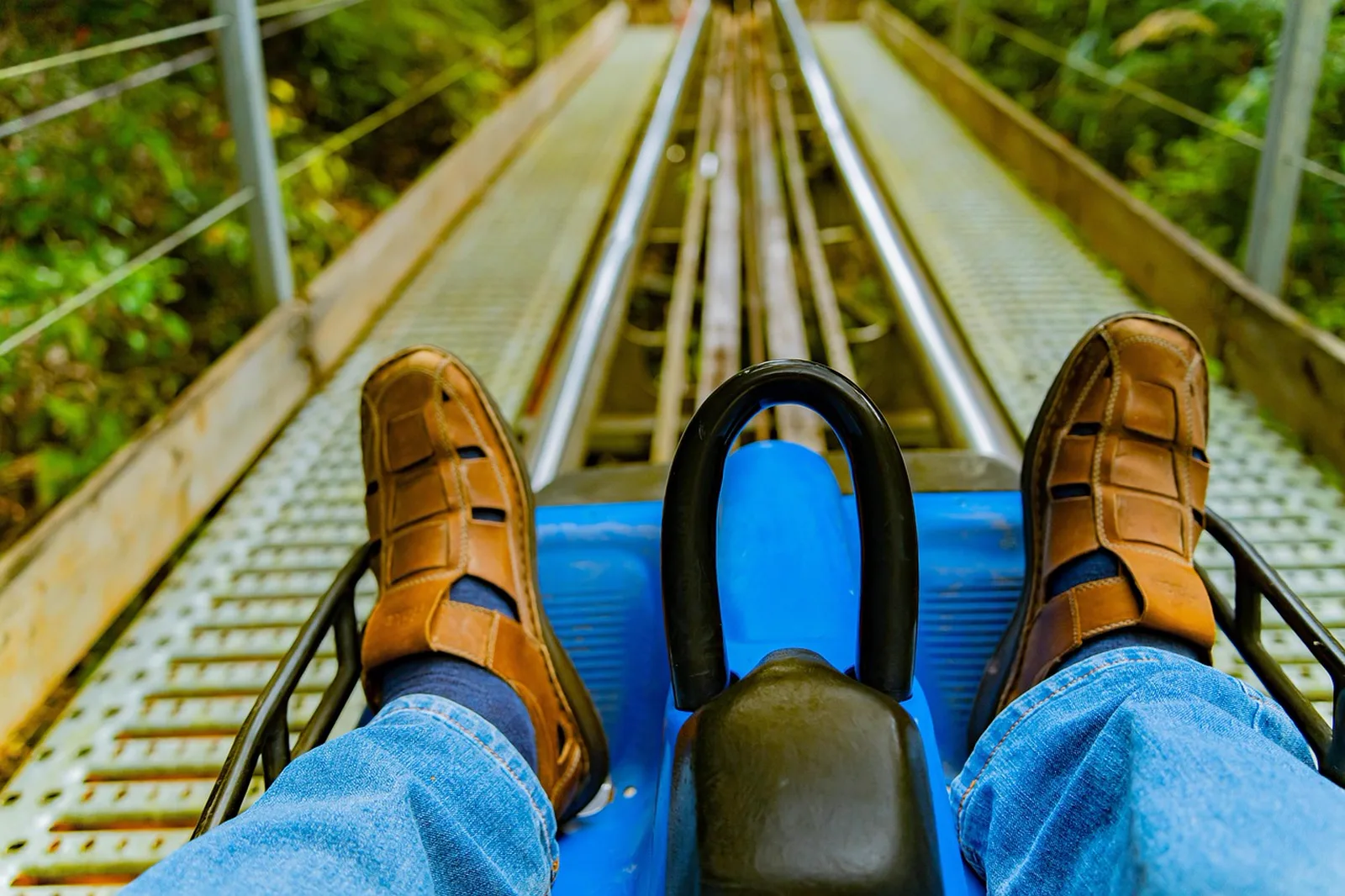 Big Thunder Mountain Railroad: A rider's point-of-view perspective sitting in a blue alpine coaster sled on steel track rails.