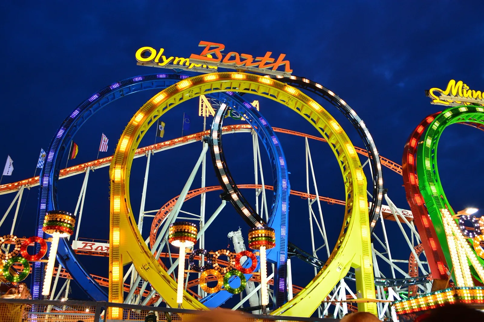 TRON Lightcycle / Run: Colorful illuminated roller coaster loops stand out against a dark evening sky.