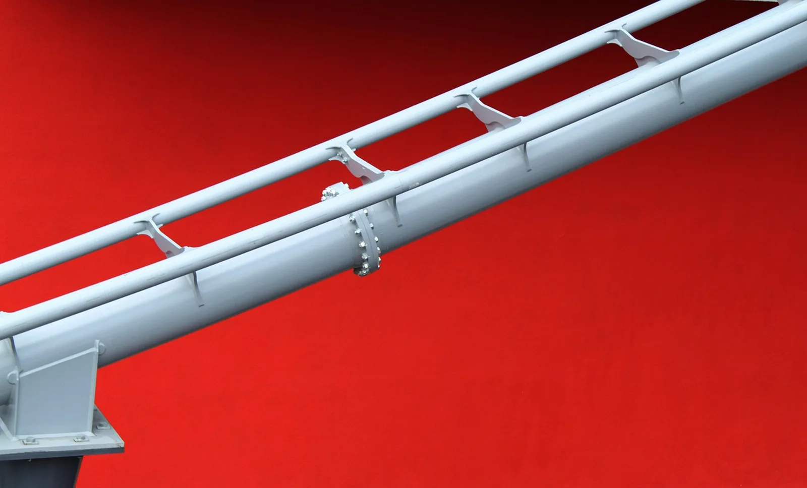 Rock 'n' Roller Coaster: A close-up view of light gray steel roller coaster track against a bright red background.