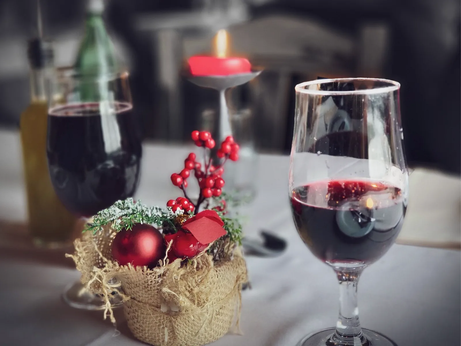 Victoria & Albert's: A close-up view of two glasses of red wine and holiday decorations set on a dining table.