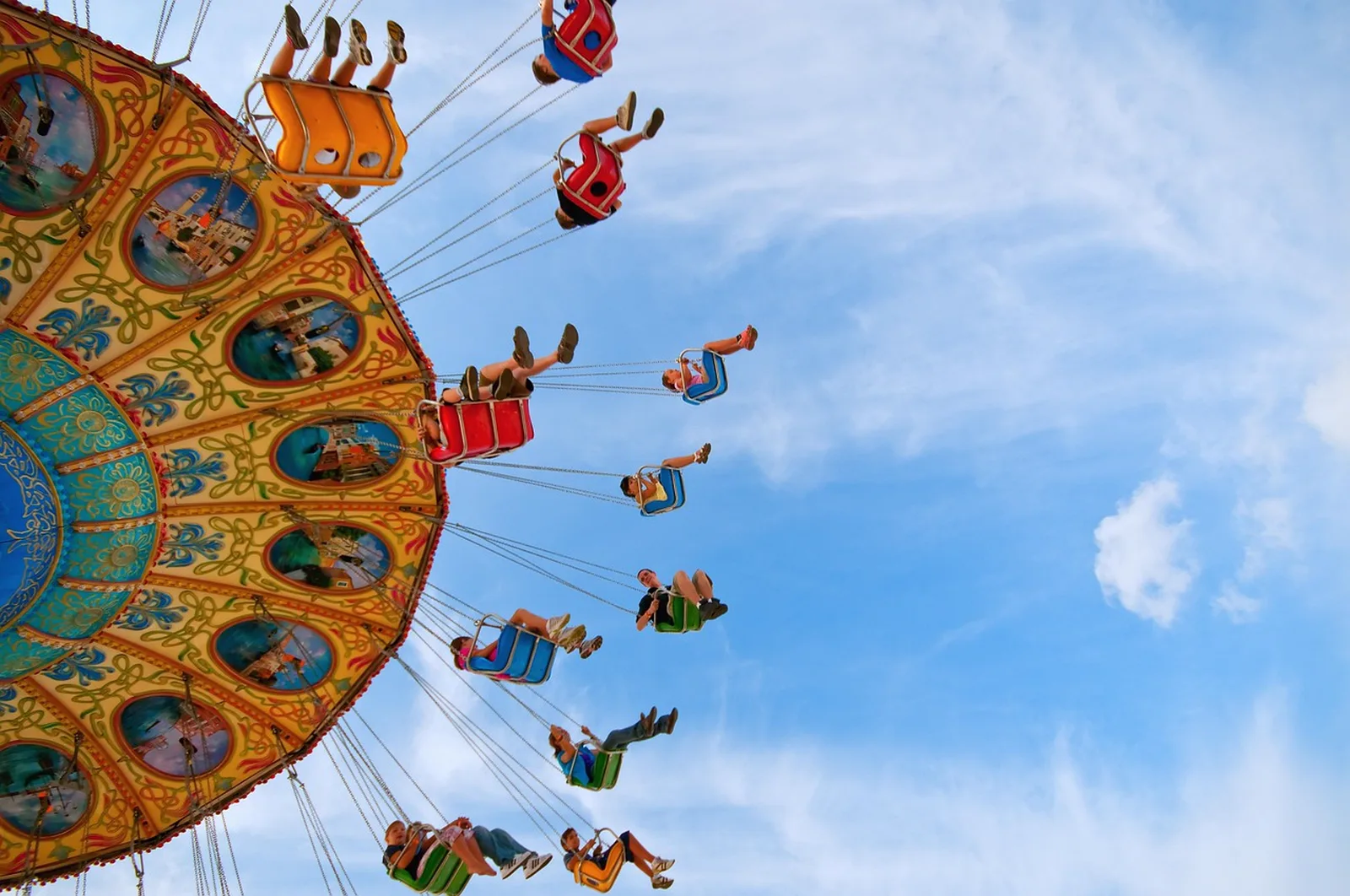 Golden Zephyr: People ride a colorful swing carousel spinning high against a blue sky.