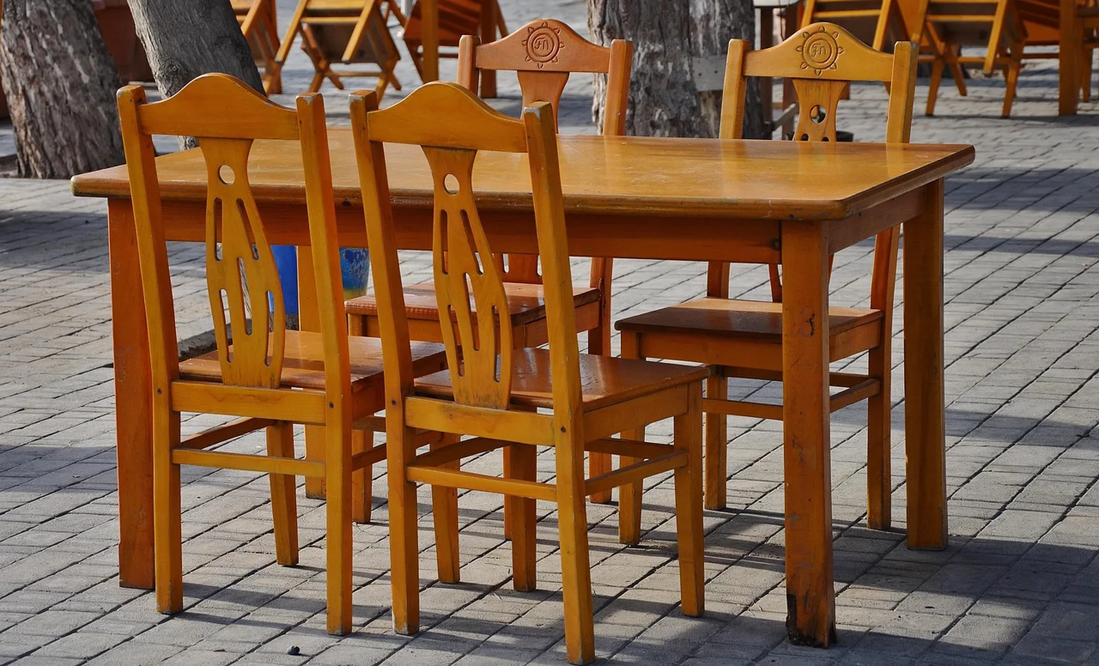 50's Prime Time Cafe: A set of wooden dining chairs surrounding a wooden table on an outdoor paved terrace.