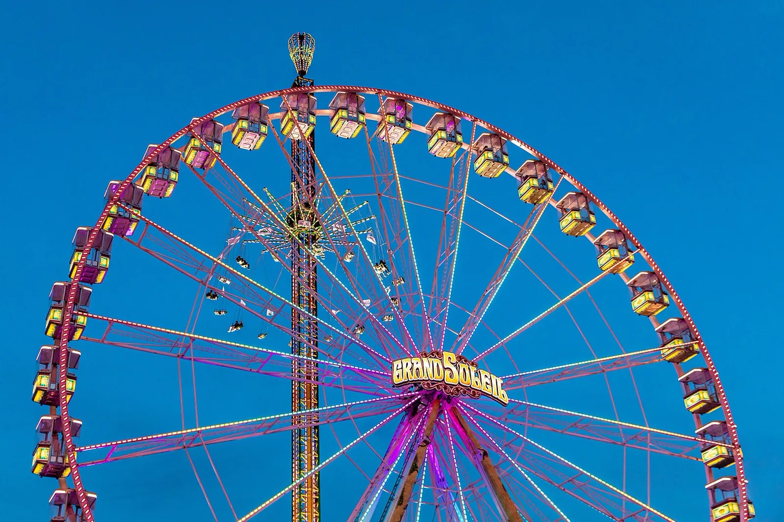 The Garland: A large illuminated Ferris wheel and swing tower against a twilight sky.
