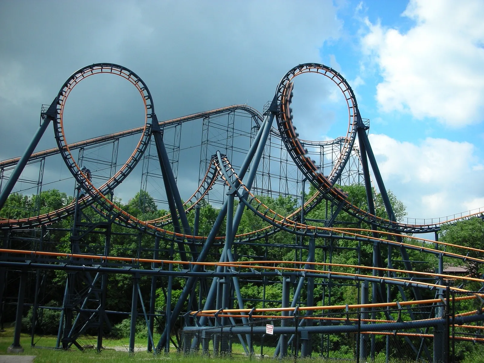 Universal Islands of Adventure: A large steel roller coaster with two large vertical loops against a partly cloudy sky.