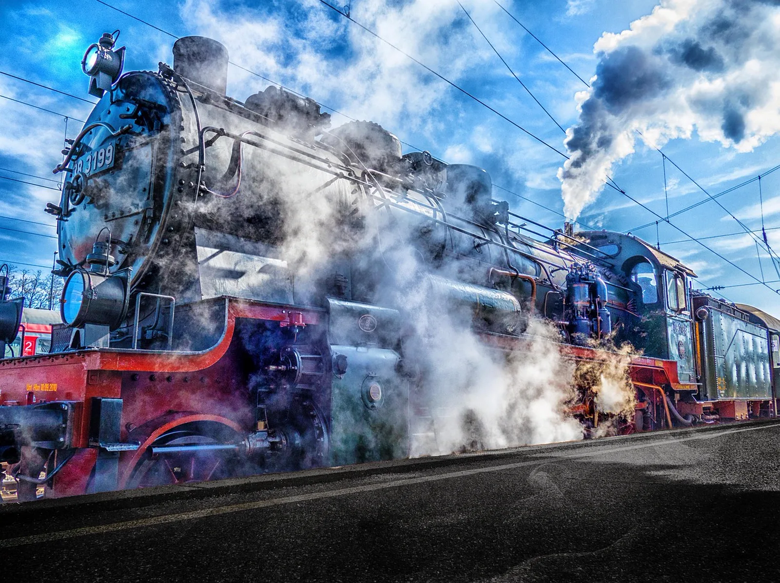 Avengers Campus: A vintage steam locomotive emits billows of steam and smoke while parked at a station platform.